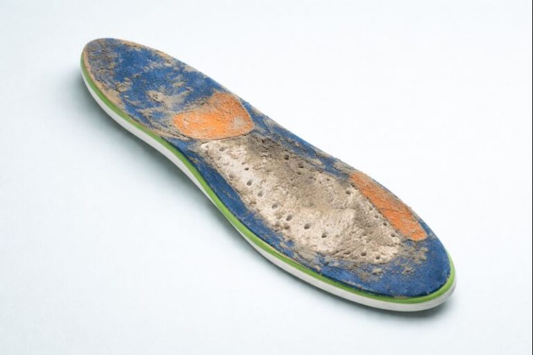 lose-up of a worn orthotic insole with visible wear and material breakdown
