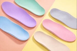 Pastel-coloured orthotic insoles arranged on a soft background, showcasing lightweight cushioning and modern insole design