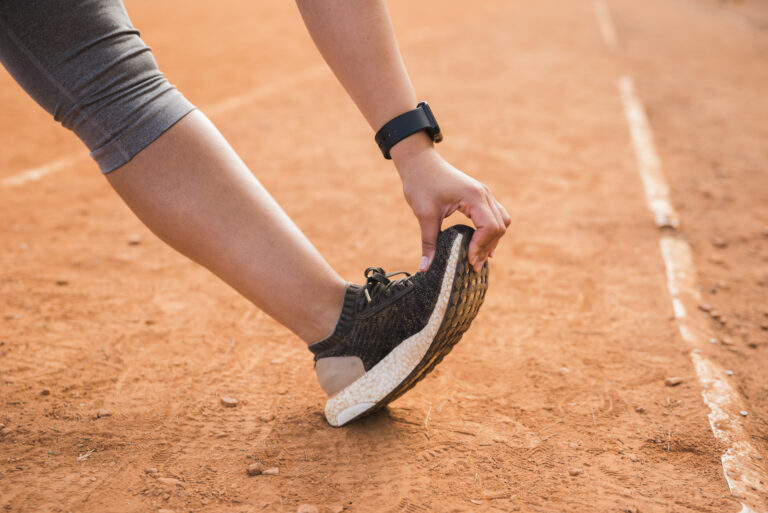 Sporty woman stretching on stadium track