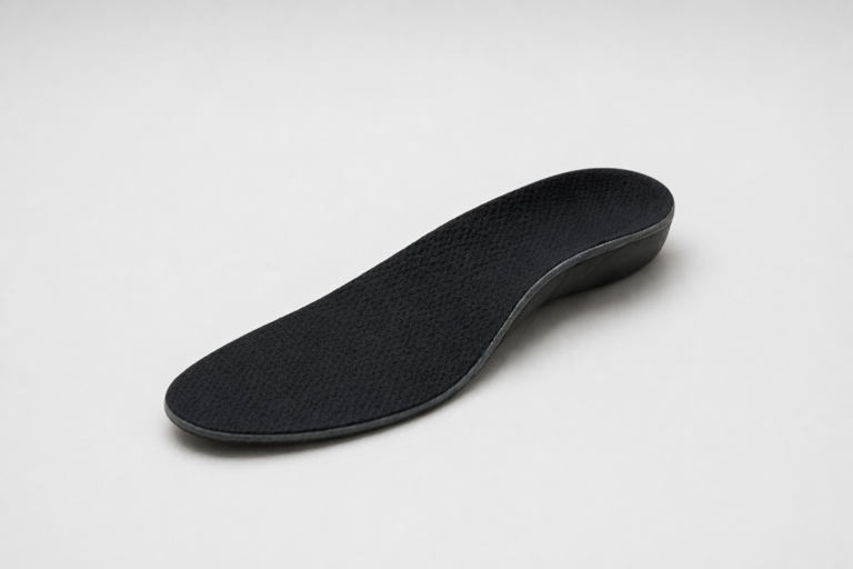 Black orthopedic shoe insole with textured surface and arch support on a light gray background